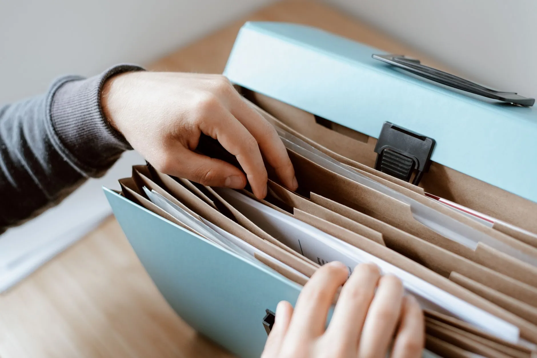 Hands going through an expanding file of paper records
